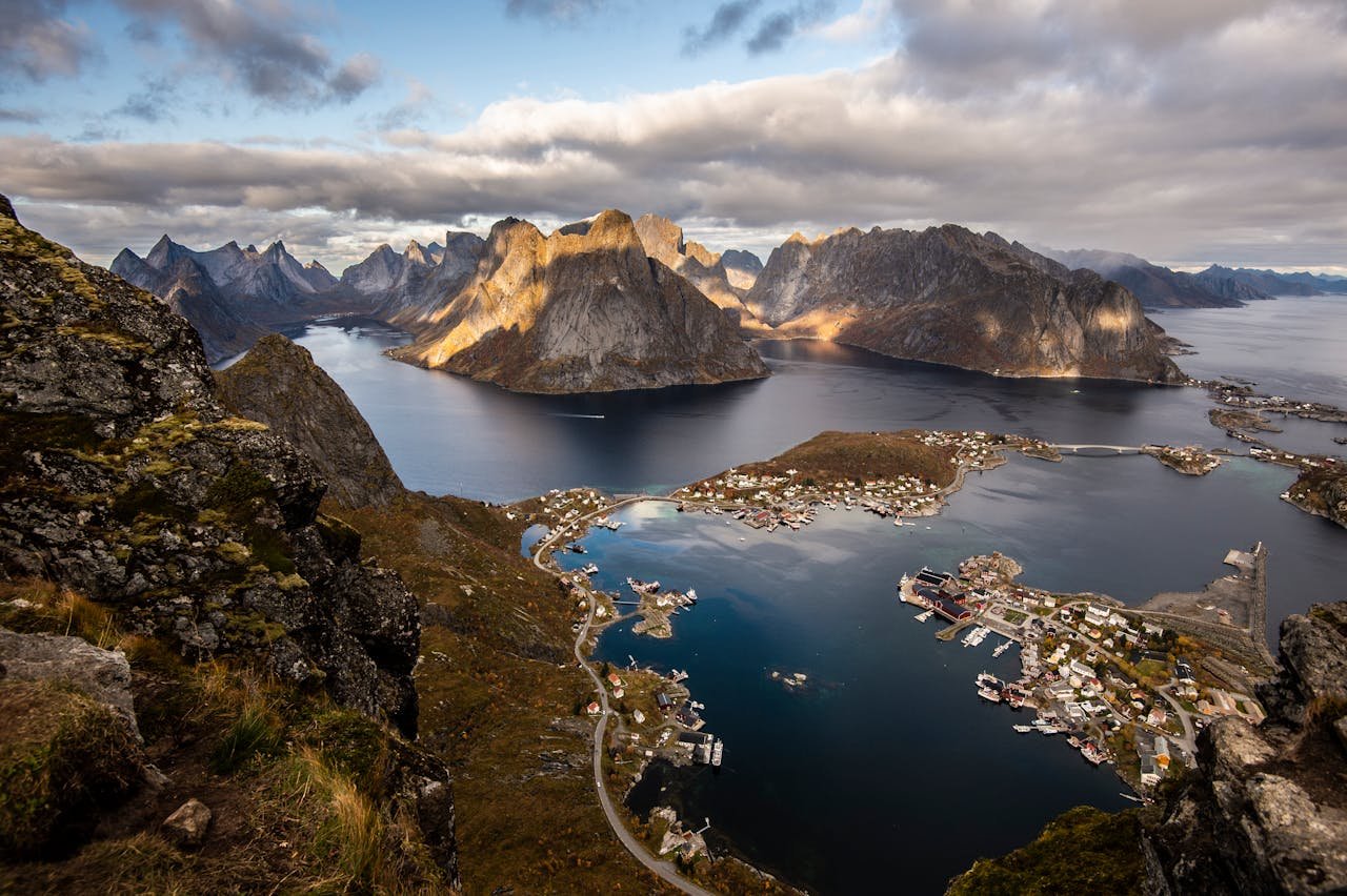 Stunning aerial view of the Reine village in Lofoten Islands, displaying dramatic mountains and serene waters.